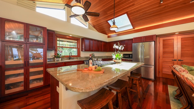 kitchen with high end refrigerator, sink, a skylight, a kitchen island, and a kitchen bar