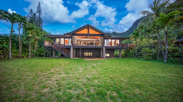 back of house featuring a deck with mountain view and a lawn