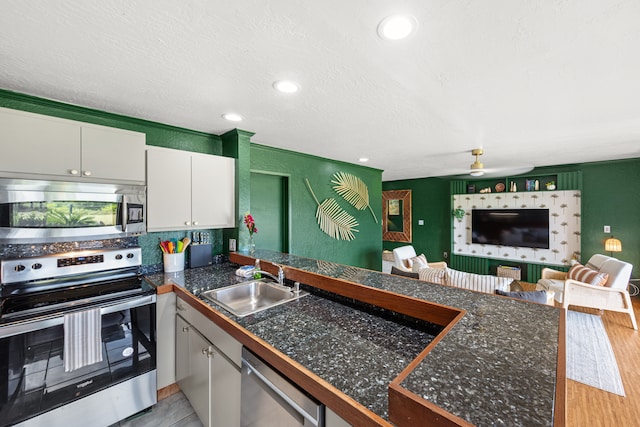 kitchen with white cabinetry, stainless steel appliances, a textured ceiling, light wood-type flooring, and sink