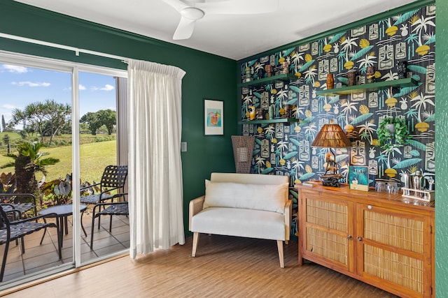 sitting room with wood-type flooring, ornamental molding, and ceiling fan