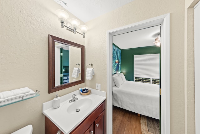 bathroom featuring vanity, a textured ceiling, hardwood / wood-style floors, and toilet