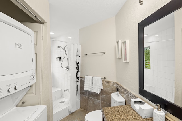 bathroom featuring stacked washer and clothes dryer, toilet, vanity, and curtained shower