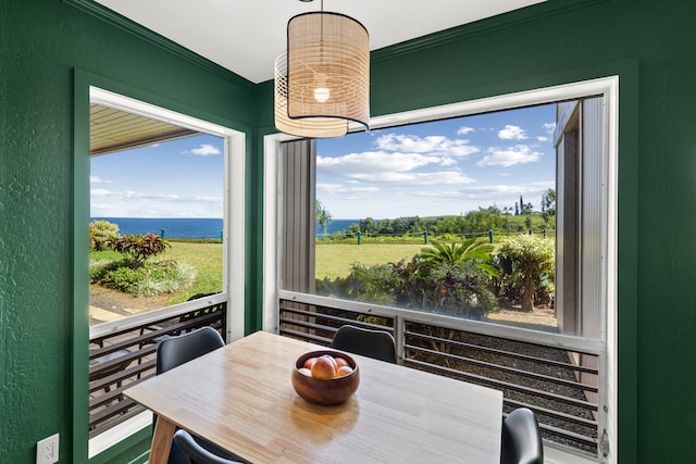 dining space featuring a water view, a healthy amount of sunlight, and crown molding