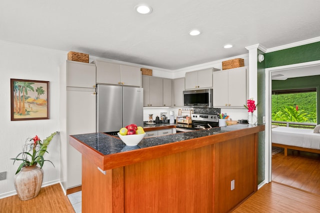 5300 Ka Haku Rd Unit 130, Princeville, HI 96722 - kitchen featuring ornamental molding, a peninsula, light wood-style floors, appliances with stainless steel finishes, and tile countertops