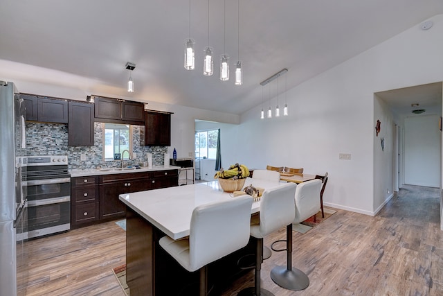 kitchen featuring light hardwood / wood-style floors, decorative light fixtures, stainless steel electric range oven, and sink