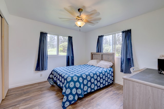 bedroom with multiple windows, wood-type flooring, and ceiling fan