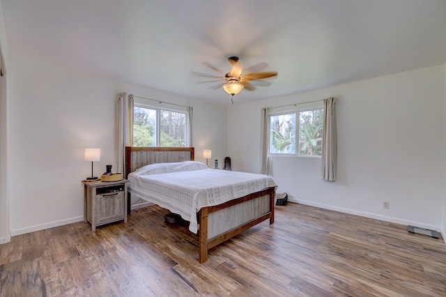 bedroom featuring multiple windows, hardwood / wood-style floors, and ceiling fan