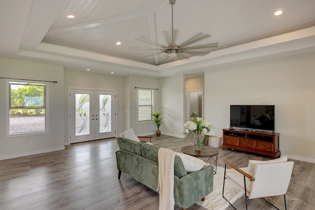 living room with hardwood / wood-style floors, french doors, a raised ceiling, and ceiling fan