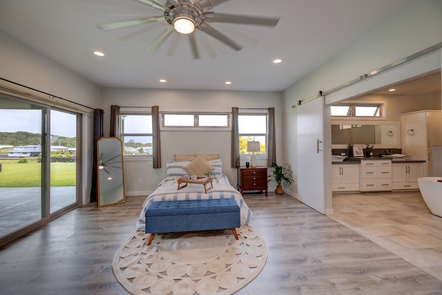 bedroom featuring access to outside, multiple windows, a barn door, and ceiling fan