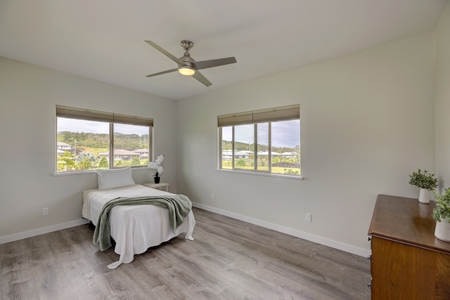 bedroom featuring multiple windows, light wood-type flooring, and ceiling fan