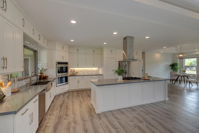 kitchen with appliances with stainless steel finishes, sink, white cabinetry, light hardwood / wood-style flooring, and exhaust hood