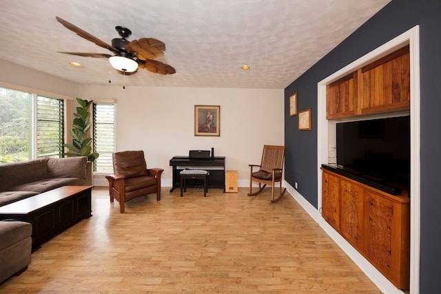 living room with light hardwood / wood-style flooring, ceiling fan, and a textured ceiling