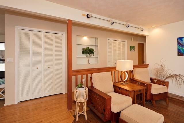 sitting room with wood-type flooring and rail lighting