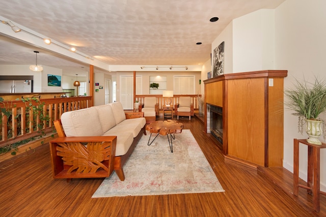 living room with a textured ceiling, dark wood-type flooring, and track lighting