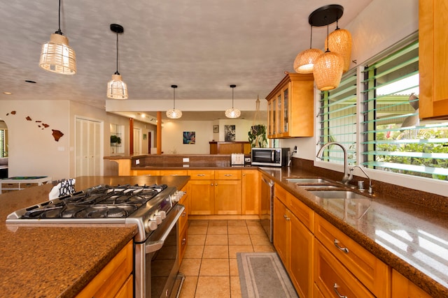 kitchen with appliances with stainless steel finishes, hanging light fixtures, light tile patterned floors, and sink