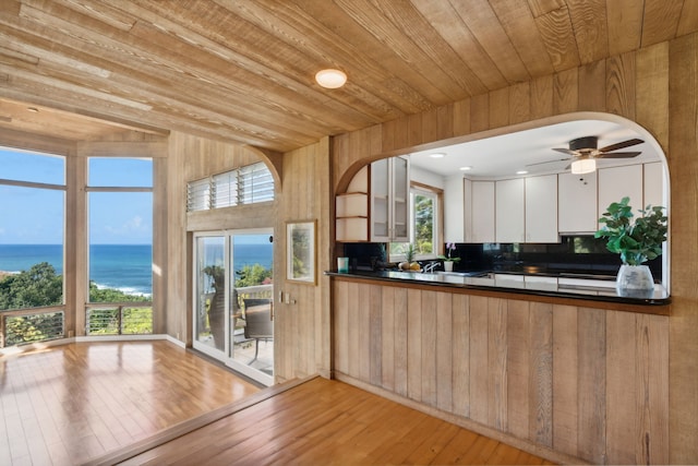 kitchen with light hardwood / wood-style floors, white cabinetry, a water view, and wood ceiling