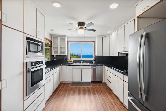 kitchen with appliances with stainless steel finishes, tasteful backsplash, sink, wood-type flooring, and white cabinets