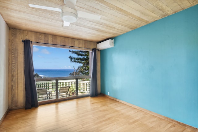 spare room with a wall mounted air conditioner, light wood-type flooring, wood ceiling, a water view, and wood walls