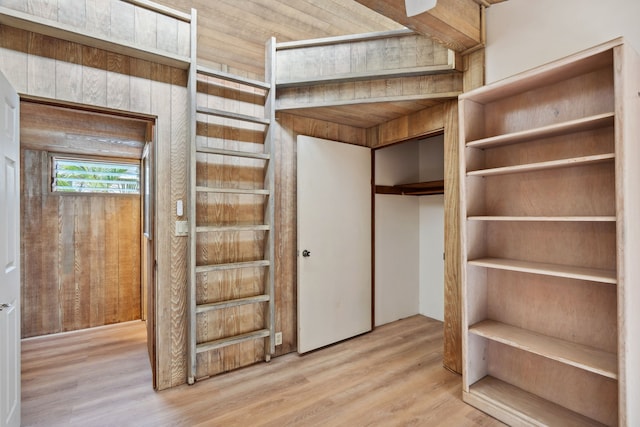 unfurnished bedroom with wooden walls, a closet, and hardwood / wood-style floors