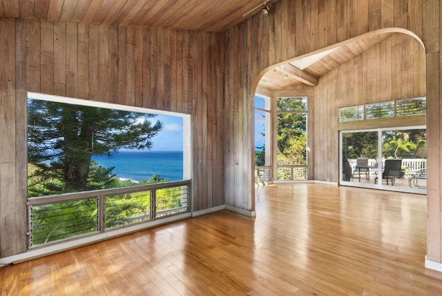 unfurnished living room featuring a water view, wooden walls, and wood ceiling