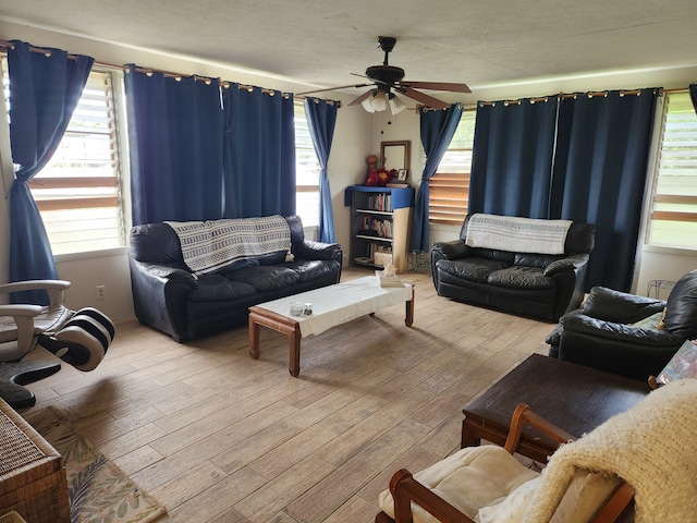 living room with light hardwood / wood-style floors, ceiling fan, and a textured ceiling