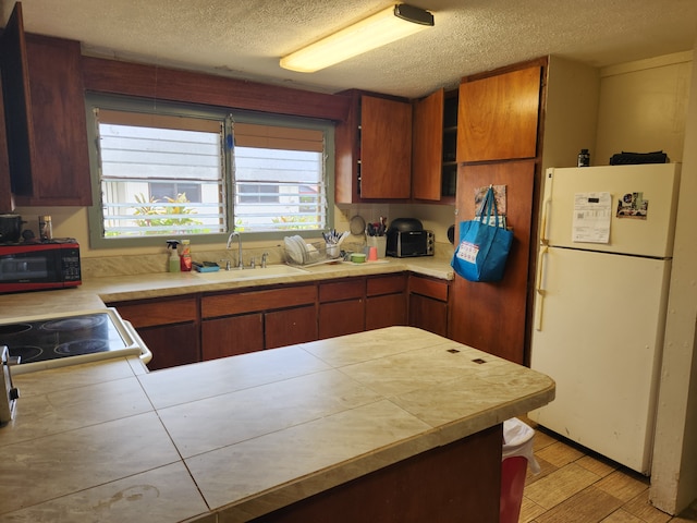 kitchen with light hardwood / wood-style floors, white refrigerator, a textured ceiling, range, and sink