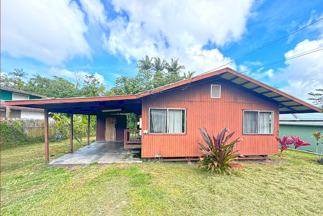 back of property with a lawn and a carport