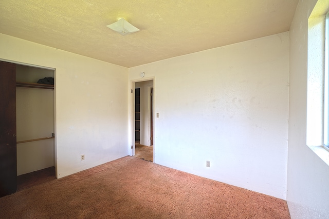 unfurnished bedroom with carpet floors, a textured ceiling, and a closet