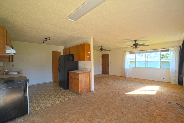 kitchen featuring ceiling fan, sink, a textured ceiling, light colored carpet, and black refrigerator