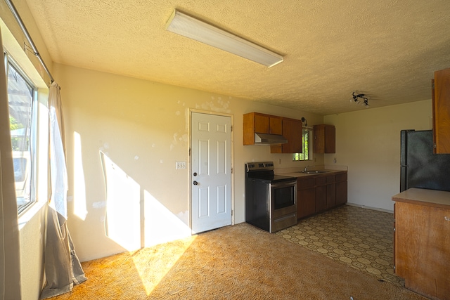 kitchen with a textured ceiling, electric range, sink, light carpet, and black refrigerator