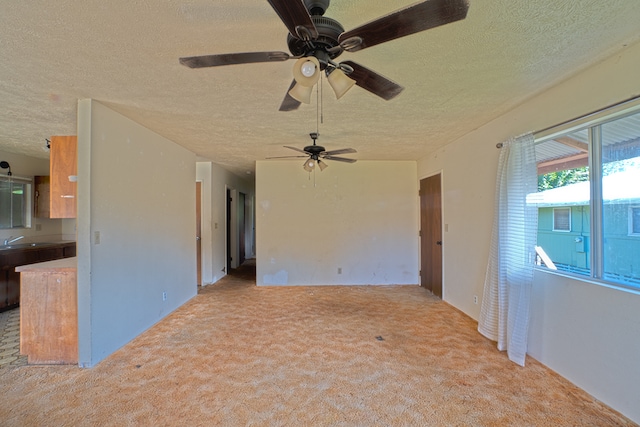 spare room featuring light carpet, a textured ceiling, sink, and ceiling fan