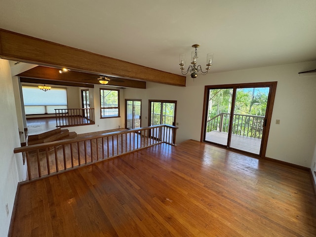 spare room featuring beamed ceiling, hardwood / wood-style floors, and a notable chandelier