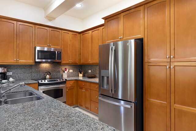 kitchen with light stone countertops, appliances with stainless steel finishes, sink, and backsplash