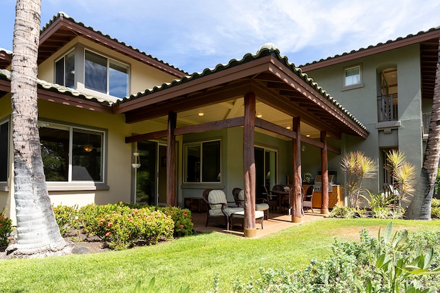 back of property featuring a patio area and a lawn