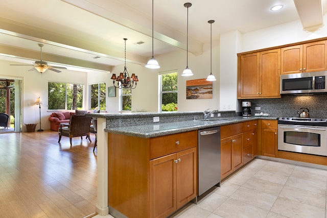 kitchen with light wood-type flooring, decorative light fixtures, stainless steel appliances, and a healthy amount of sunlight