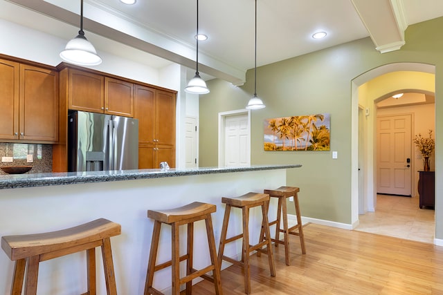 kitchen with stainless steel fridge, light hardwood / wood-style flooring, decorative light fixtures, and backsplash