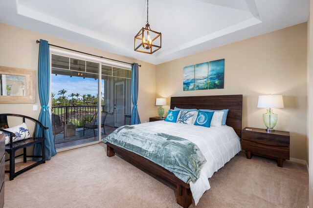 carpeted bedroom with access to outside, an inviting chandelier, and a raised ceiling