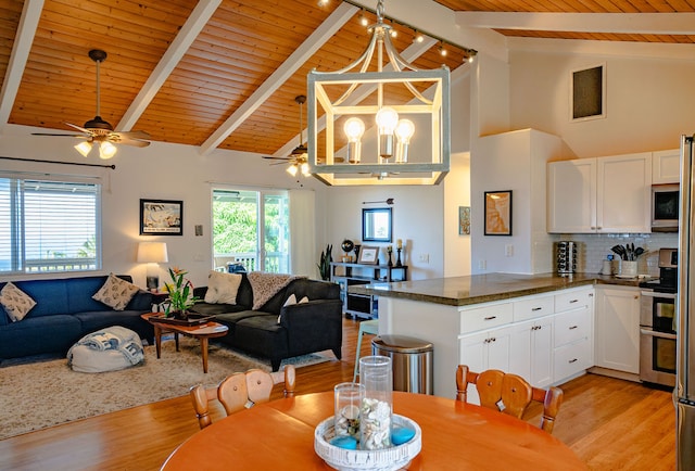 dining space with ceiling fan with notable chandelier, high vaulted ceiling, beamed ceiling, and light hardwood / wood-style flooring