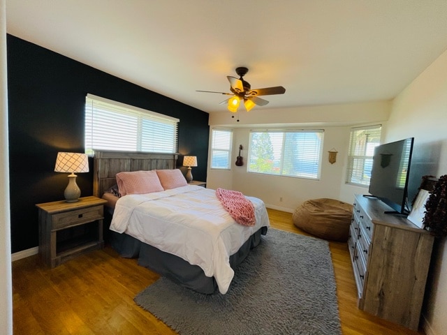 bedroom featuring ceiling fan, light hardwood / wood-style flooring, and multiple windows