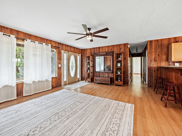 living room featuring wooden walls, ceiling fan, and light hardwood / wood-style flooring