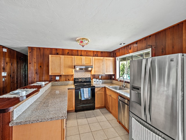 kitchen with decorative backsplash, wooden walls, appliances with stainless steel finishes, and sink