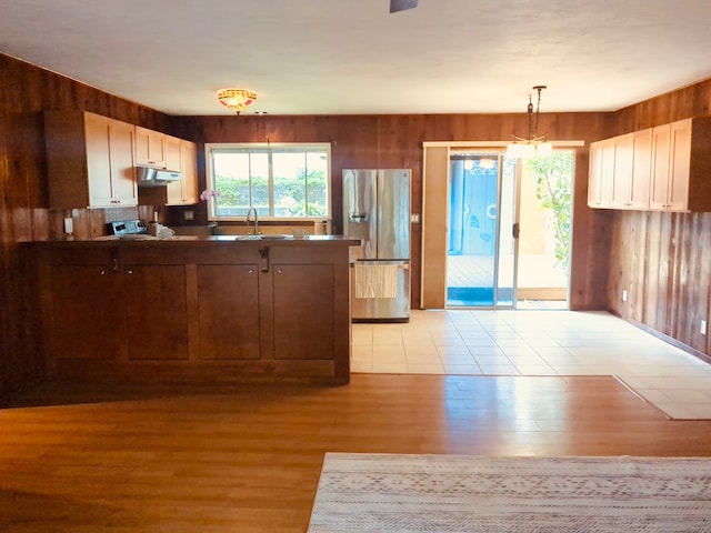 kitchen featuring light wood-type flooring, white cabinetry, hanging light fixtures, and stainless steel fridge