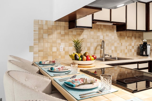 kitchen with a sink, stove, tasteful backsplash, and light countertops