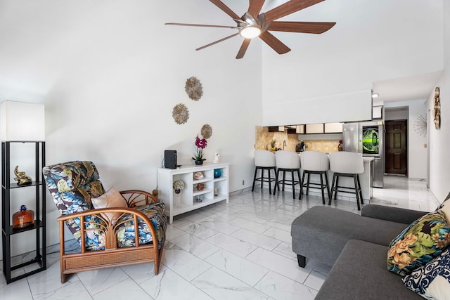 living room featuring marble finish floor, a towering ceiling, and ceiling fan
