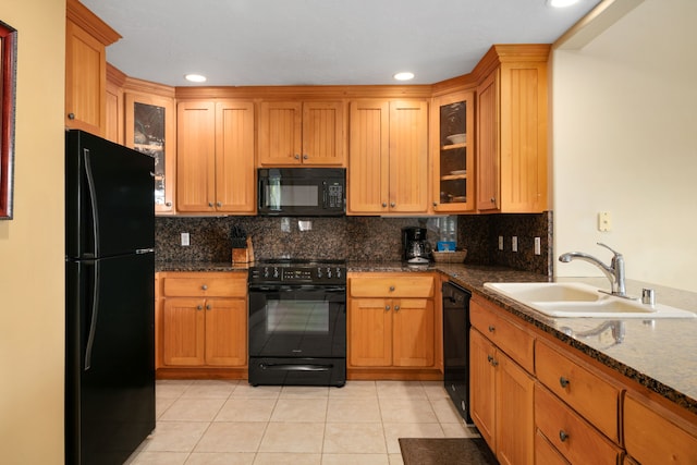 kitchen with black appliances, sink, light tile patterned flooring, backsplash, and dark stone countertops