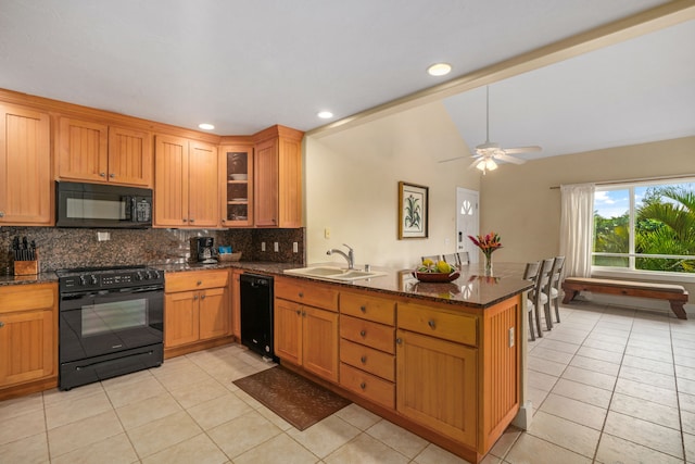 kitchen featuring black appliances, dark stone counters, sink, vaulted ceiling, and kitchen peninsula