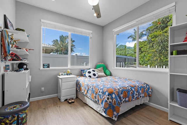 bedroom featuring ceiling fan, hardwood / wood-style floors, and multiple windows