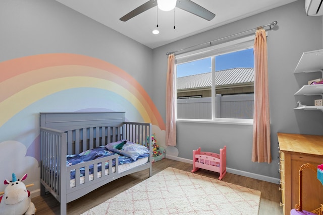 bedroom featuring ceiling fan, a wall mounted air conditioner, and wood-type flooring