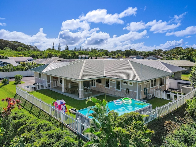 back of property featuring a patio, a lawn, and a fenced in pool