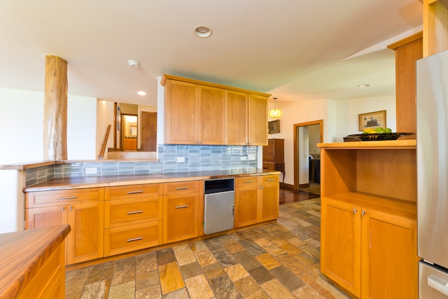 kitchen featuring stainless steel refrigerator, hanging light fixtures, and backsplash